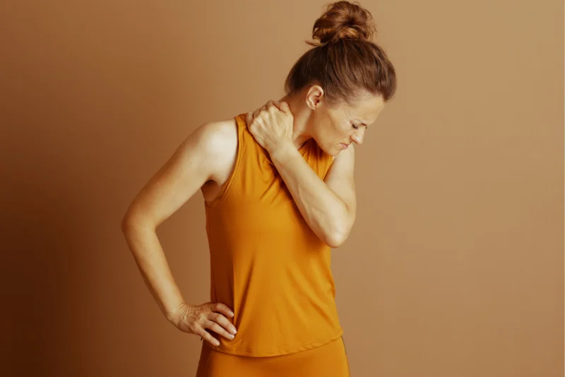 A woman grips and ruber her neck tension with one hand looking down to the other side