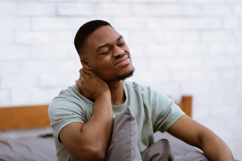 Person holding the back of their neck, illustrating neck pain and instability in hypermobility