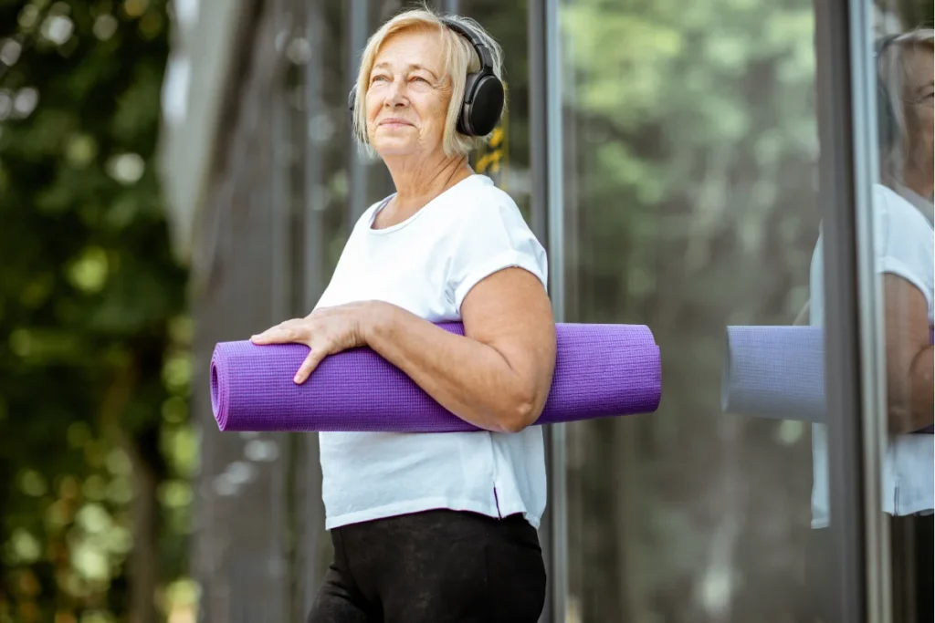 a woman wearing headphones and holding an exercise mat