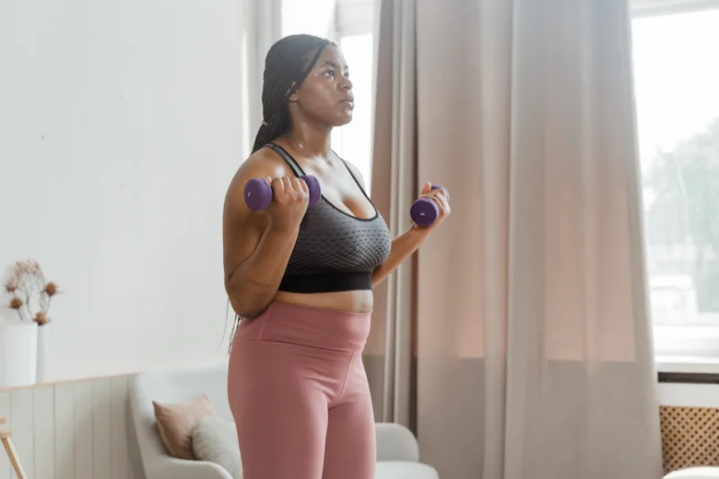 a woman in exercise close doing bicep curls with small hand weights 