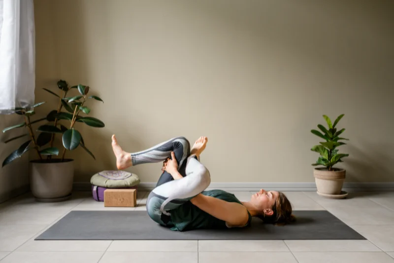 a woman on a yoga mat does a figure 4 stretch 