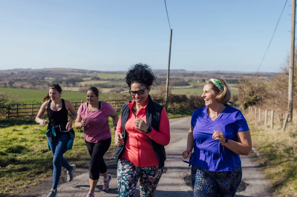 Two woman in colorful clothes are walking and laughing on a country road.